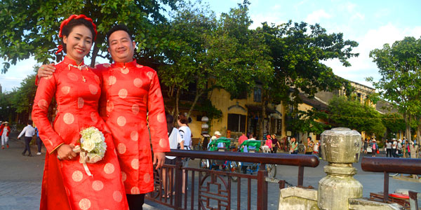 Red tunics donned, a couple poses on the bridge at Hoi An - photo: Vijay Verghese